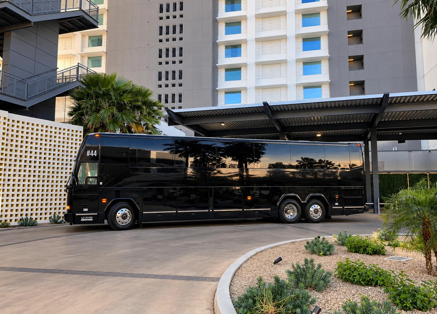Black 44 passenger luxury coach party bus parked at a Southern California hotel entrance