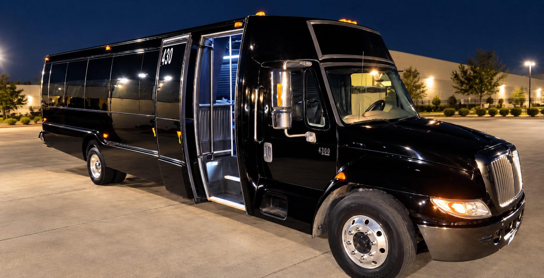 Black 30 passenger party bus at night with entry door open and interior lighting on